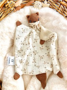 a brown teddy bear laying on top of a white blanket next to a wicker basket