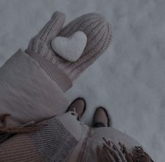 someone wearing mittens and gloves with a white heart on their thumb, standing in the snow