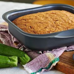 a loaf of bread sitting on top of a wooden cutting board next to cucumbers