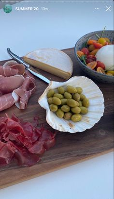 an assortment of meats, cheese and olives on a cutting board with bread