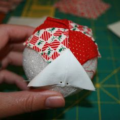 someone is making something out of fabric with scissors and glue on the ball, which looks like an ornament