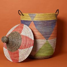 two woven baskets with lids and handles on an orange background