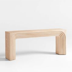 a wooden bench sitting on top of a white floor next to a wall in the shape of an arch