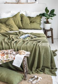 an unmade bed with green sheets and pillows on top of the bedspread