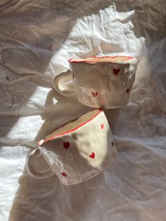 two cups with hearts on them sitting on a sheet