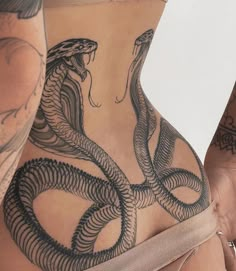 two women with tattoos on their stomachs and one has a snake tattooed on the side