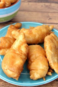 some fried food is on a blue plate and next to two bowls with dipping sauces