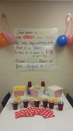 a table topped with lots of food and cups filled with popcorn next to some balloons