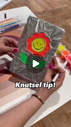 a person holding a piece of tin foil with a flower on it and the words knustsel tip