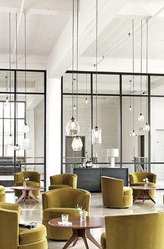 the interior of a modern restaurant with yellow chairs and round tables in front of large glass windows