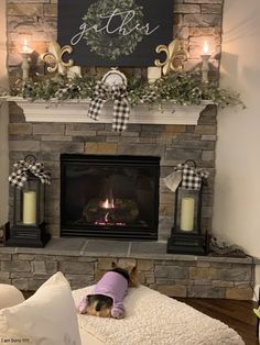 a dog laying on a blanket in front of a fire place with candles and wreaths