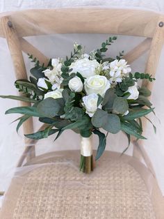 a bouquet of white flowers sitting on top of a wooden chair