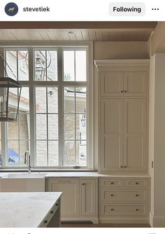 a kitchen with white cabinets and an island in front of a window that has a lantern hanging from the ceiling