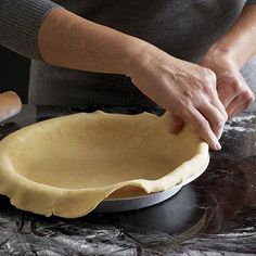 a woman is making an uncooked pie on a black table with a rolling pin