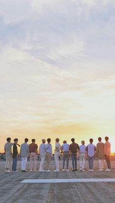 a group of men standing on top of an airport tarmac with the sun setting in the background