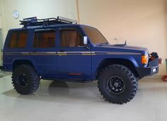 a large blue suv parked inside of a garage next to a clock on the wall