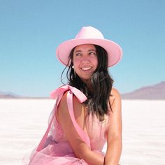 a woman in a pink dress and hat sitting on the ground