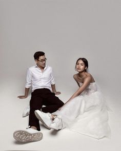 a man sitting next to a woman in a white dress on top of a floor