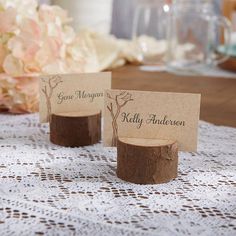 two place cards sitting on top of a table next to a vase with flowers in it