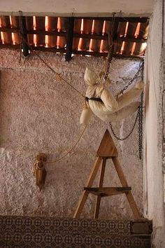 a wooden ladder with chains hanging from it's sides in front of a stone wall