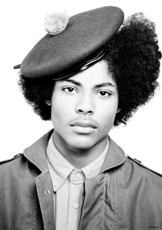 a black and white photo of a young man wearing a hat with an afro on it