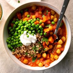 a bowl filled with peas, carrots and chickpeas topped with sour cream