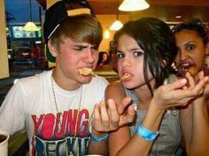 two young people eating donuts at a table in a restaurant while another person looks on