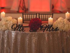 a table topped with flowers and candles next to a couple's names on top of it