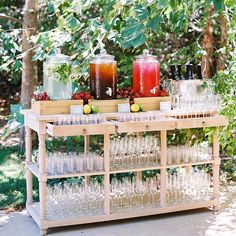 an outdoor bar with glasses, lemons and drinks on the table in front of some trees