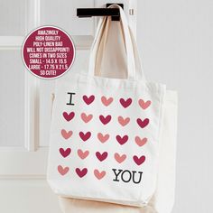 a tote bag with hearts on it hanging from a hook in front of a door