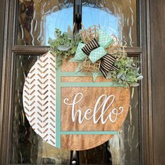 a wooden sign that says hello hanging on the front door with green and white decorations