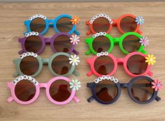 several pairs of sunglasses with flowers on them sitting on top of a wooden table next to each other