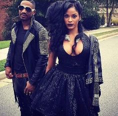 a man and woman walking down the street in front of each other wearing black outfits