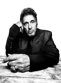 a black and white photo of a man sitting at a table with his hand on his head