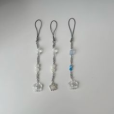 three necklaces are hanging on a white surface with blue beads and silver chains attached to them