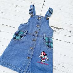 Crafted from 100% cotton denim, this overall dress offers both comfort and durability for your little one's adventures. Adorned with Minnie Mouse embroidery and green plaid pockets, this dress has retro flair and timeless style. The brass buttons down the front add an extra touch of vintage charm, completing the look. Designed in a size 4, this overall dress ensures a comfortable fit for your toddler. Whether it's a playdate or a family outing, she'll be ready to steal the show in this adorable vintage-inspired dress. Mouse Embroidery, Brass Buttons, Denim Overall Dress, Family Outing, Overall Dress, Inspired Dress, Green Plaid, Blue Jean, Timeless Style