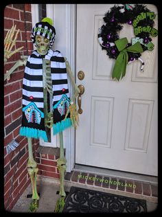 a skeleton dressed up as a clown standing in front of a door