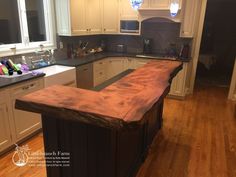 an island in the middle of a kitchen with white cabinets and wood flooring on it