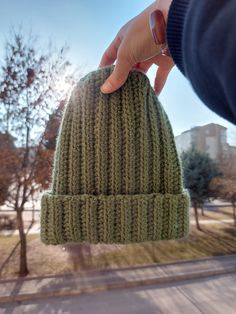 a person holding up a green knitted hat