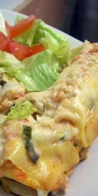 a white plate topped with an enchilada covered in cheese and lettuce