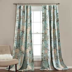 a living room with a chair and window covered in blue floral print curtain drapes