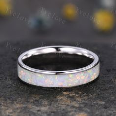 a wedding ring with white opal inlaying the center on a granite surface