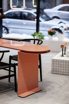 an orange table with two black chairs and a white car parked in the back ground