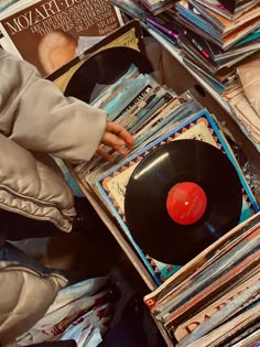 a person holding a record in front of a pile of records