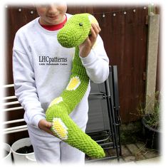 a young boy holding up a green knitted snake