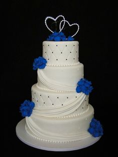 a white wedding cake with blue flowers and hearts on top