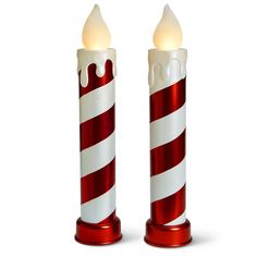 two red and white candles with lights on each candle holder are standing side by side in the shape of candy canes