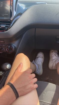 two people sitting in the driver's seat of a car with their feet propped up