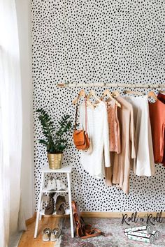 clothes hanging on a rack in front of a polka dot wall