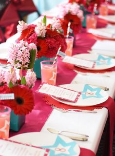 the table is set with pink and red flowers